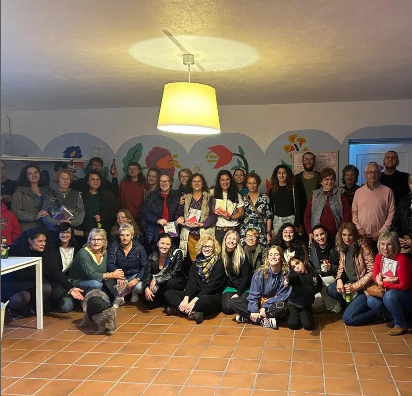 Grupo reunido en la Casa do Pobo de Anceu, bajo el mural de flores y la lámpara amarilla