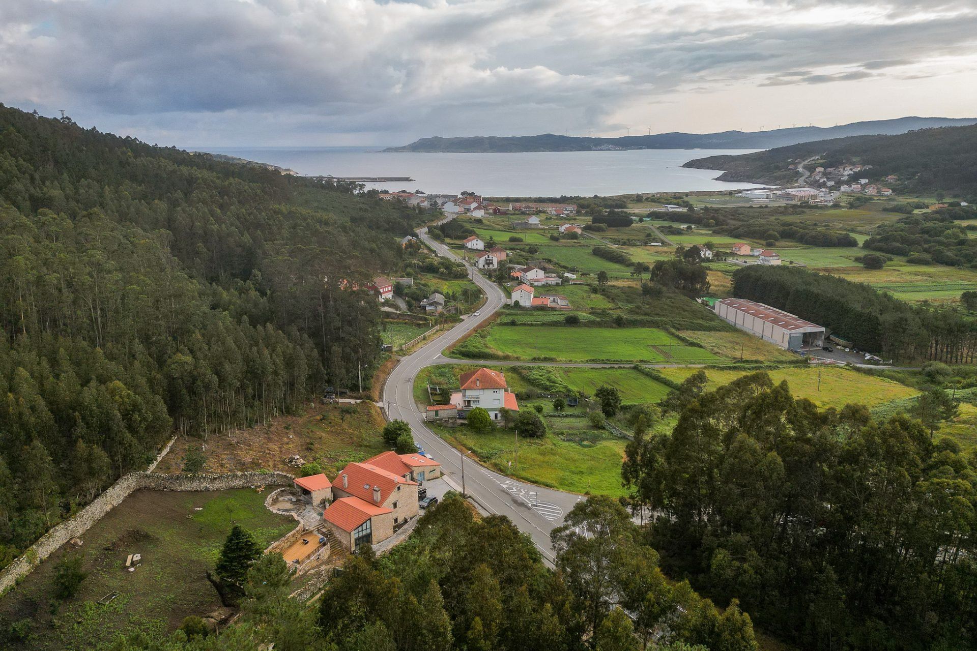 Vista aérea del entorno rural de iSlow en Laxe, con casas de piedra y la ría al fondo