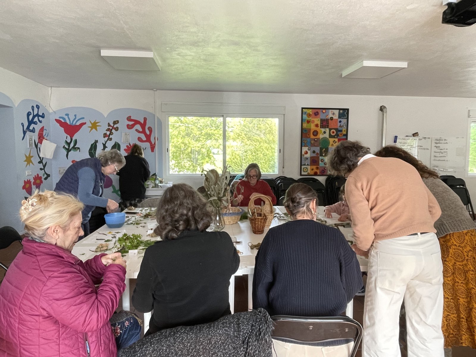 Taller comunitario de arte botánico alrededor de una mesa larga en Anceu
