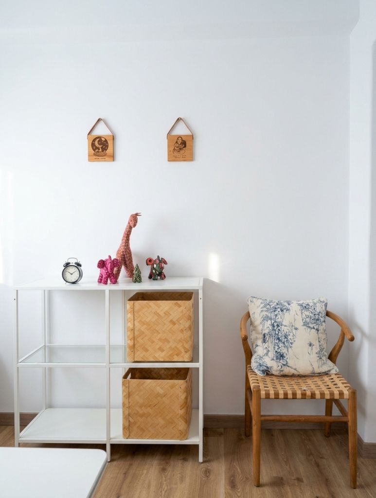 Rincón de Sala L con estantería blanca, peluches, cestas de mimbre, silla de madera con cojín toile y placas en la pared