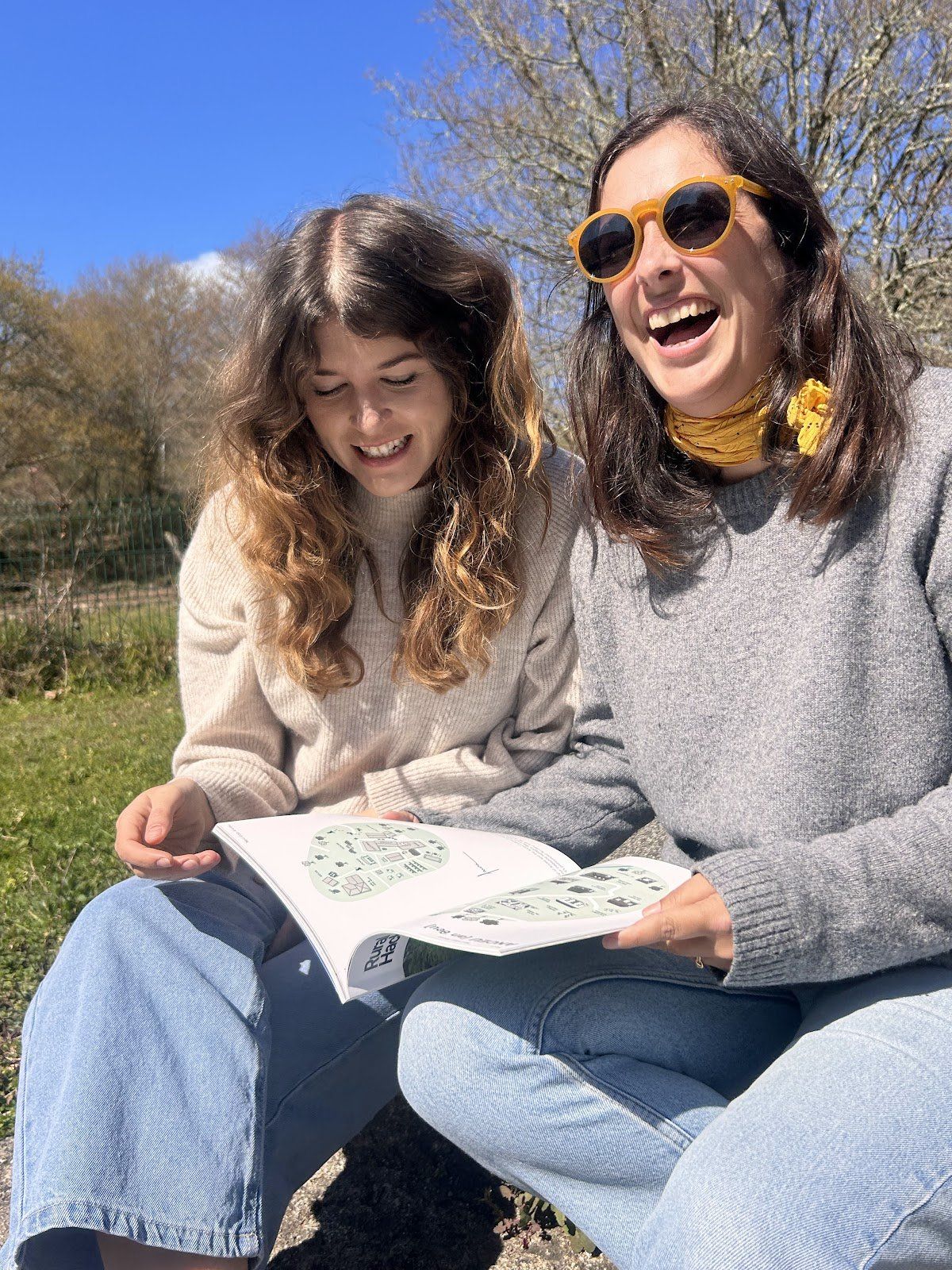 Dos compañeras en Anceu comparten una revista de Rural Hackers al aire libre