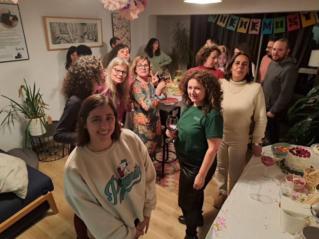Grupo de personas celebrando en comunidad en el coworking Espacio Arroelo en Pontevedra, con tarta, vino y ambiente alegre