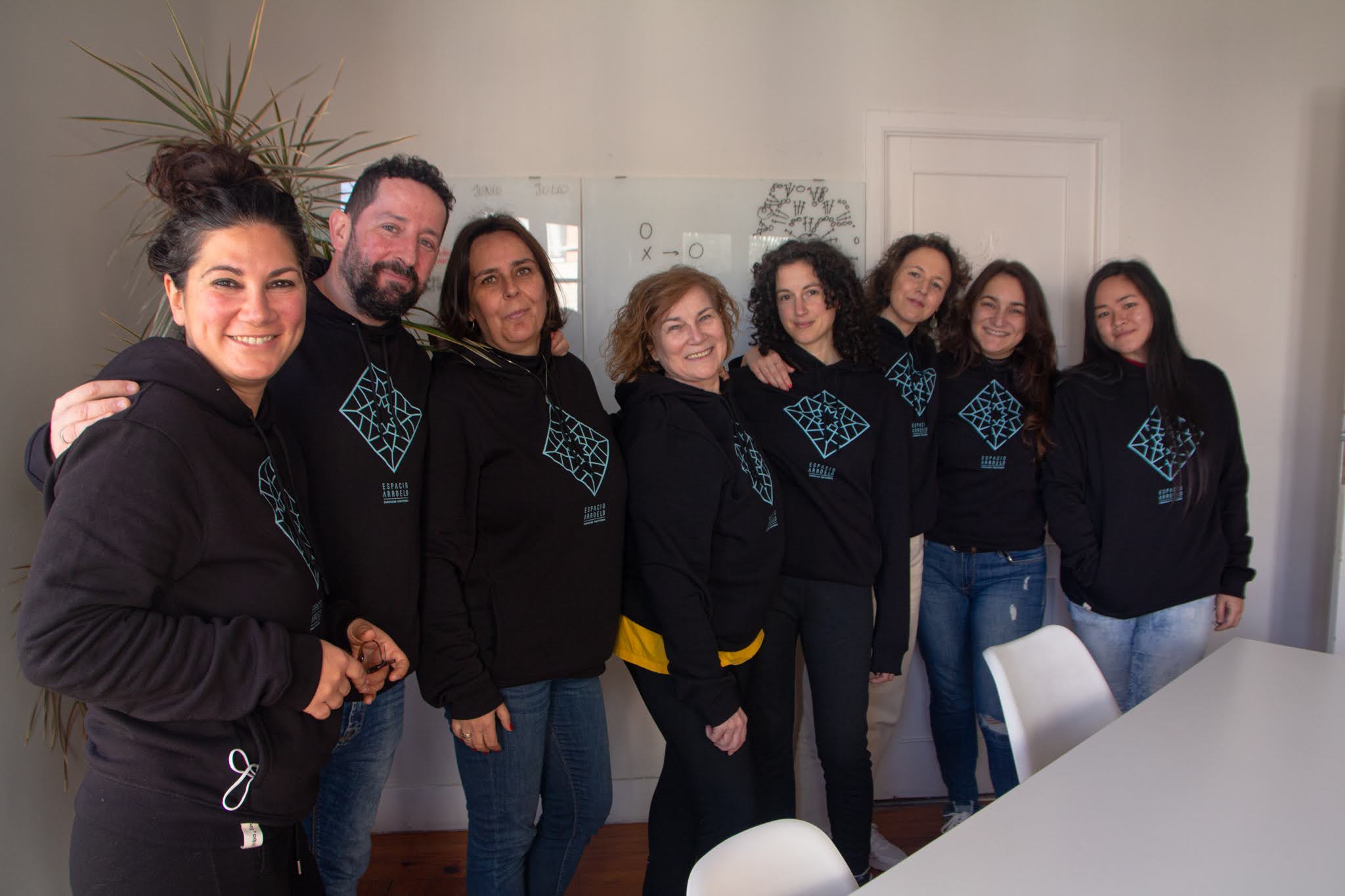 Comunidad de Espacio Arroelo con sudaderas del coworking de Pontevedra frente a una pizarra