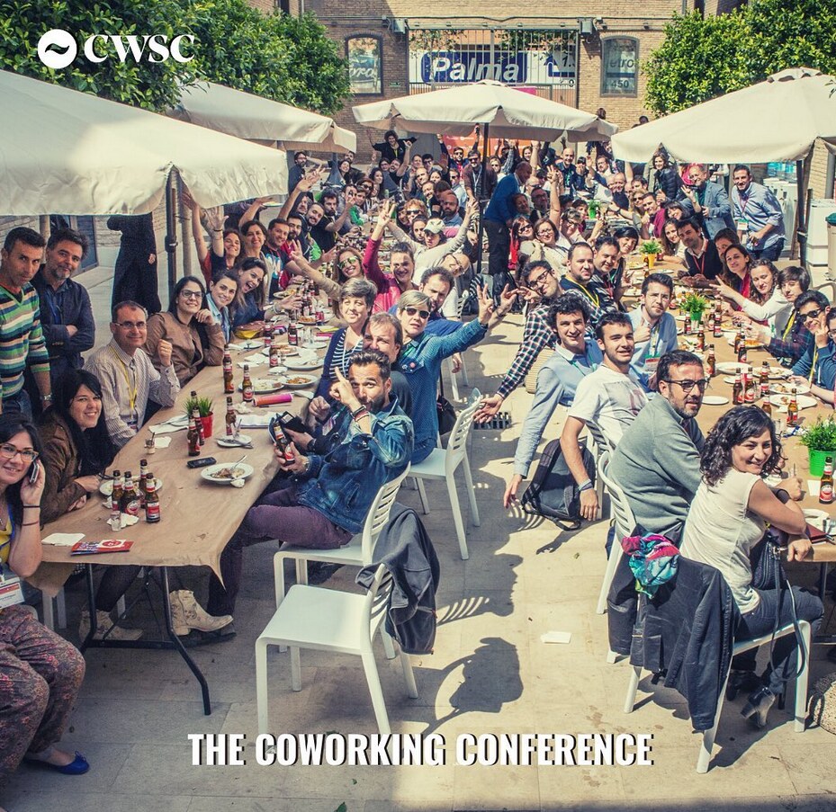 Grupo de asistentes de la Coworking Spain Conference comiendo juntos al aire libre bajo sombrillas