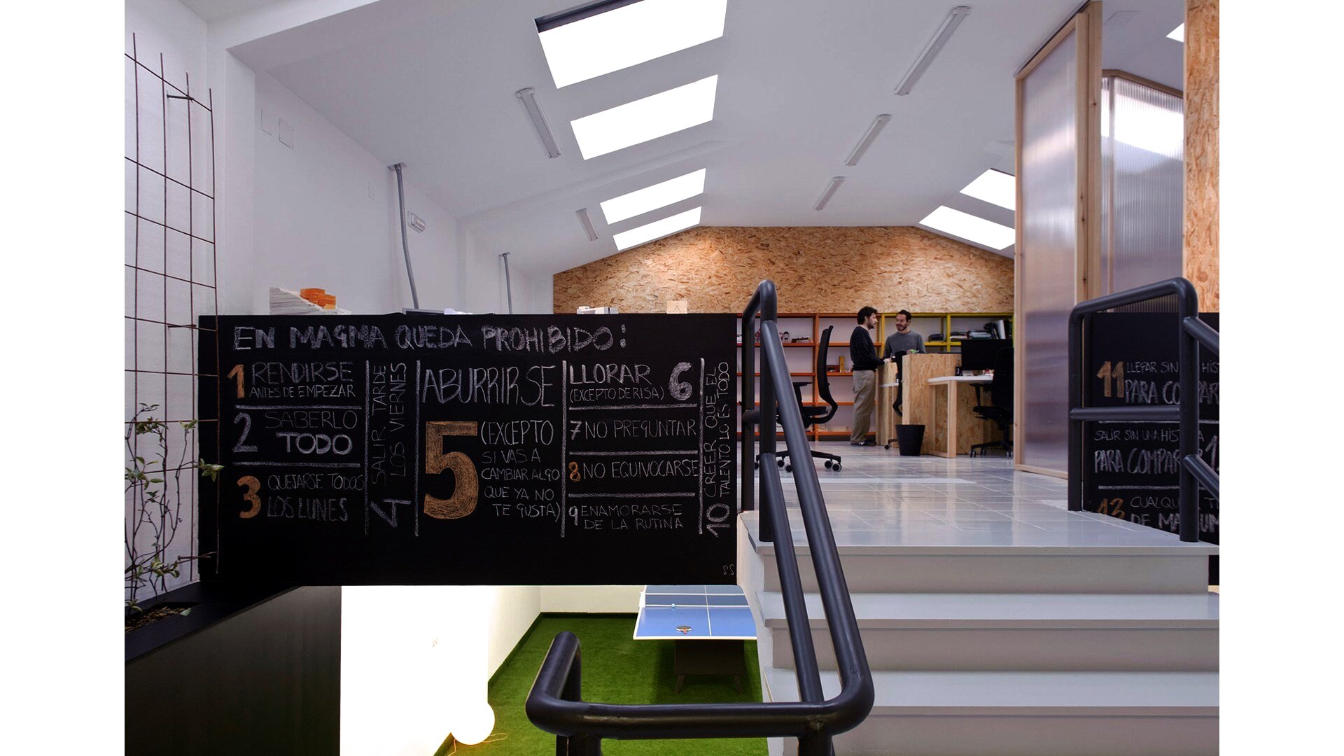 Interior de Magma Espacio en Ourense: pizarra de normas de la comunidad, puestos de coworking y zona de ping-pong