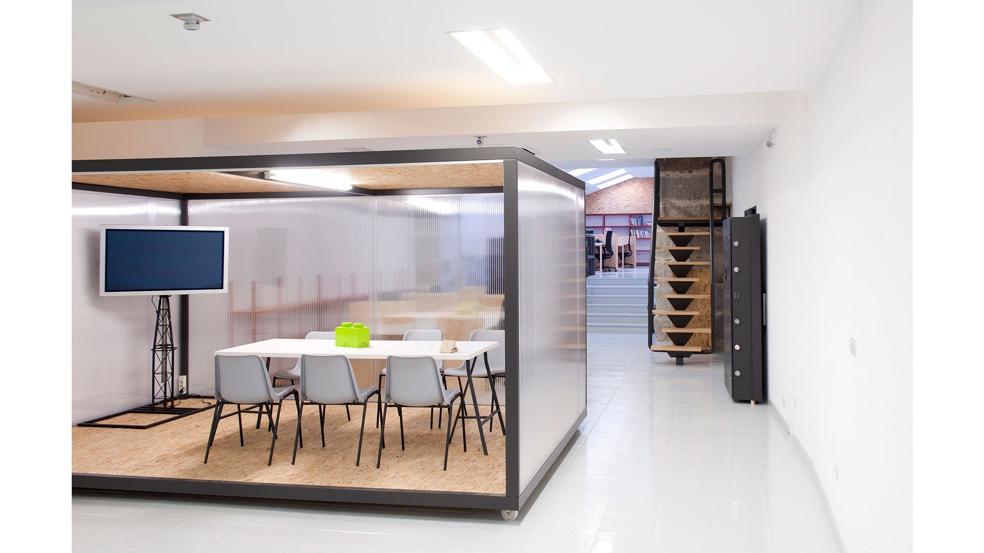 Sala de reuniones móvil de Magma Espacio en Ourense, con mesas blancas y estructura de OSB
