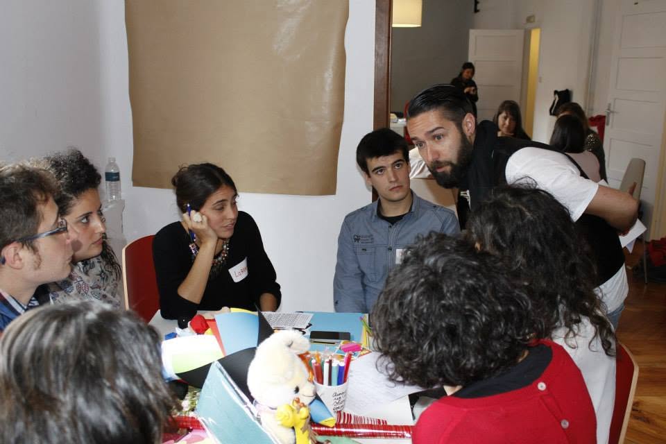 Facilitador inclinándose sobre la mesa con un equipo durante la prototipación en la Jam