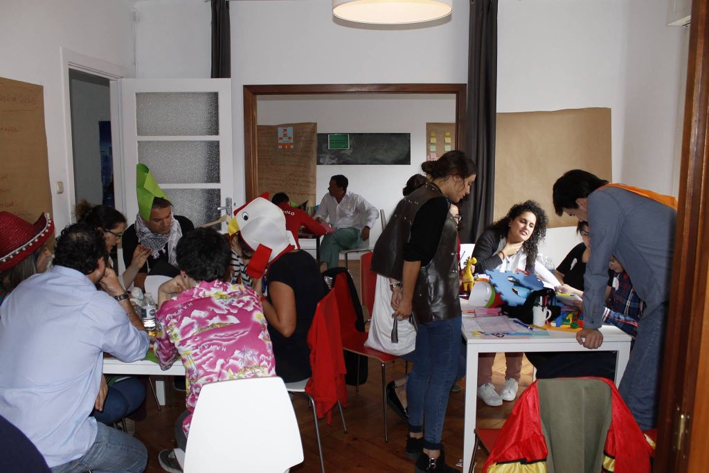 Sala de taller con equipos prototipando y participantes con sombreros disparatados durante una Jam